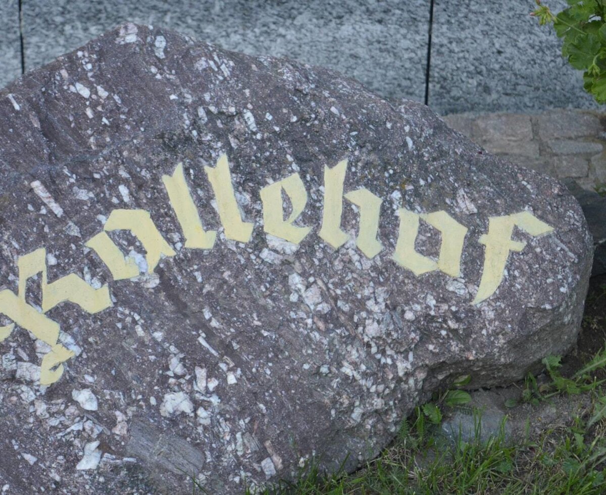 A rock sign displaying "Kallehof," the name of the Farm House.