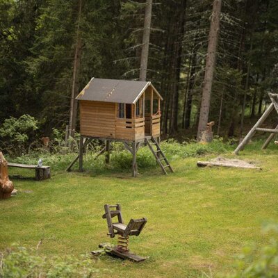 Playground at the Alm with a stilt playhouse and a spring rider.