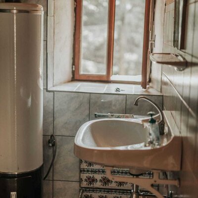 Bathroom in the Alm with a sink, water heater, and window.