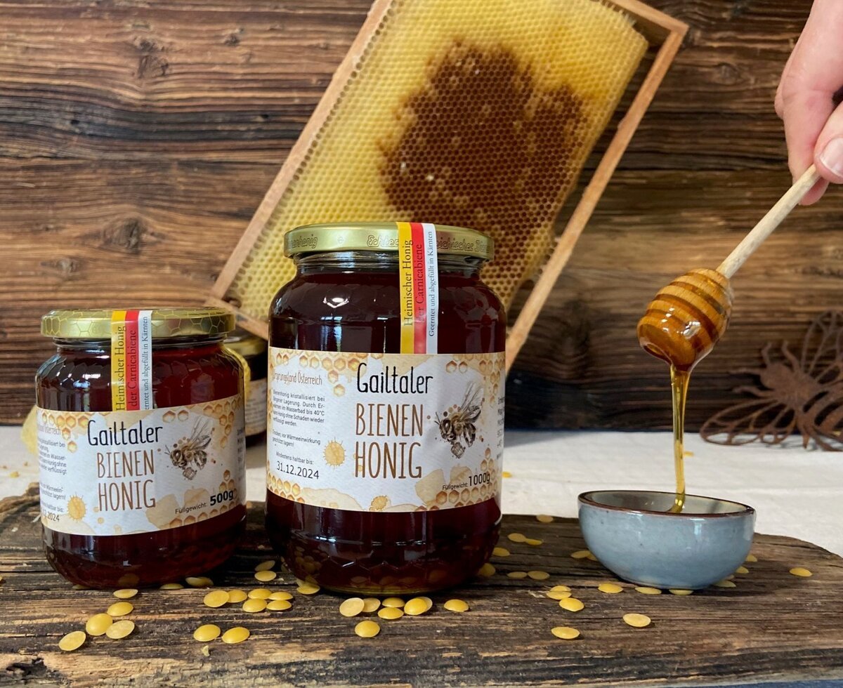 Jars of local Gailtaler bee honey, with a honeycomb and a honey dipper, showcasing products available at the farm house.