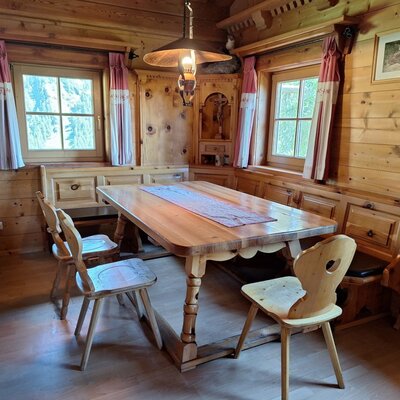 A cozy dining area in the Alm featuring a rustic wooden table, comfortable corner seating, and traditional wood-paneled walls.
