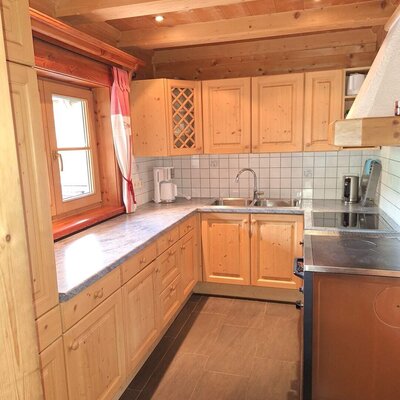 The cozy kitchen of the Alm features rustic wooden cabinetry, modern appliances, and warm ceiling lighting.