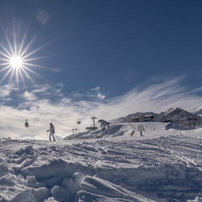 Ski slopes with skiers and gondola lifts under a sunny sky, indicating accessible winter sports for guests of the Farm House.