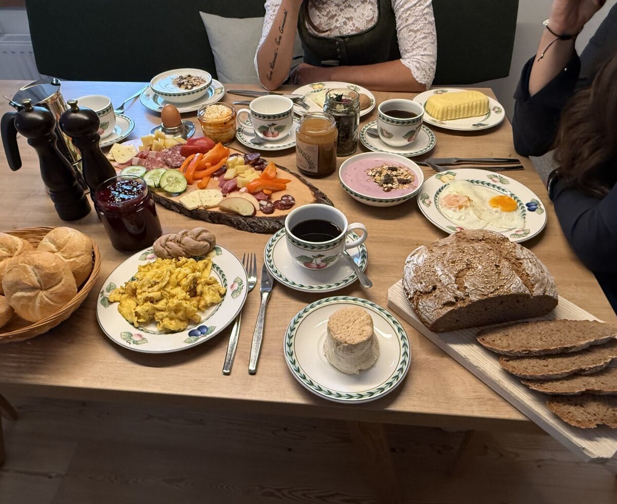 Breakfast table at the farmhouse, offering a selection of eggs, bread, cold cuts, cheese, jam, and coffee.