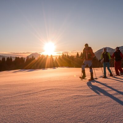 Snowshoeing on a snowy field with mountains and a winter forest, indicating outdoor activity opportunities near the Farm House.