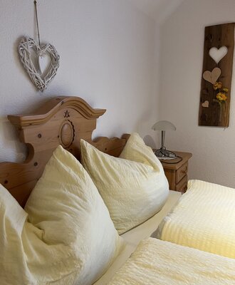 Double bedroom in the Farm House, featuring a wooden bed frame, light bedding, a bedside table with a lamp, and country-style wall decor.