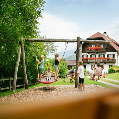 Farmhouse children's playground with swings and other play equipment.
