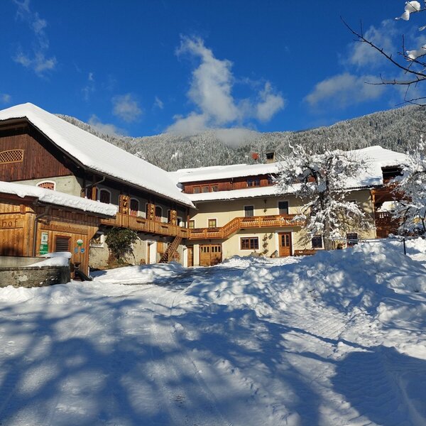 The Farm House exterior covered in snow, set against a backdrop of snow-capped mountains and a clear blue sky. The Farm House exterior covered in snow, set against a backdrop of snow-capped mountains and a clear blue sky.