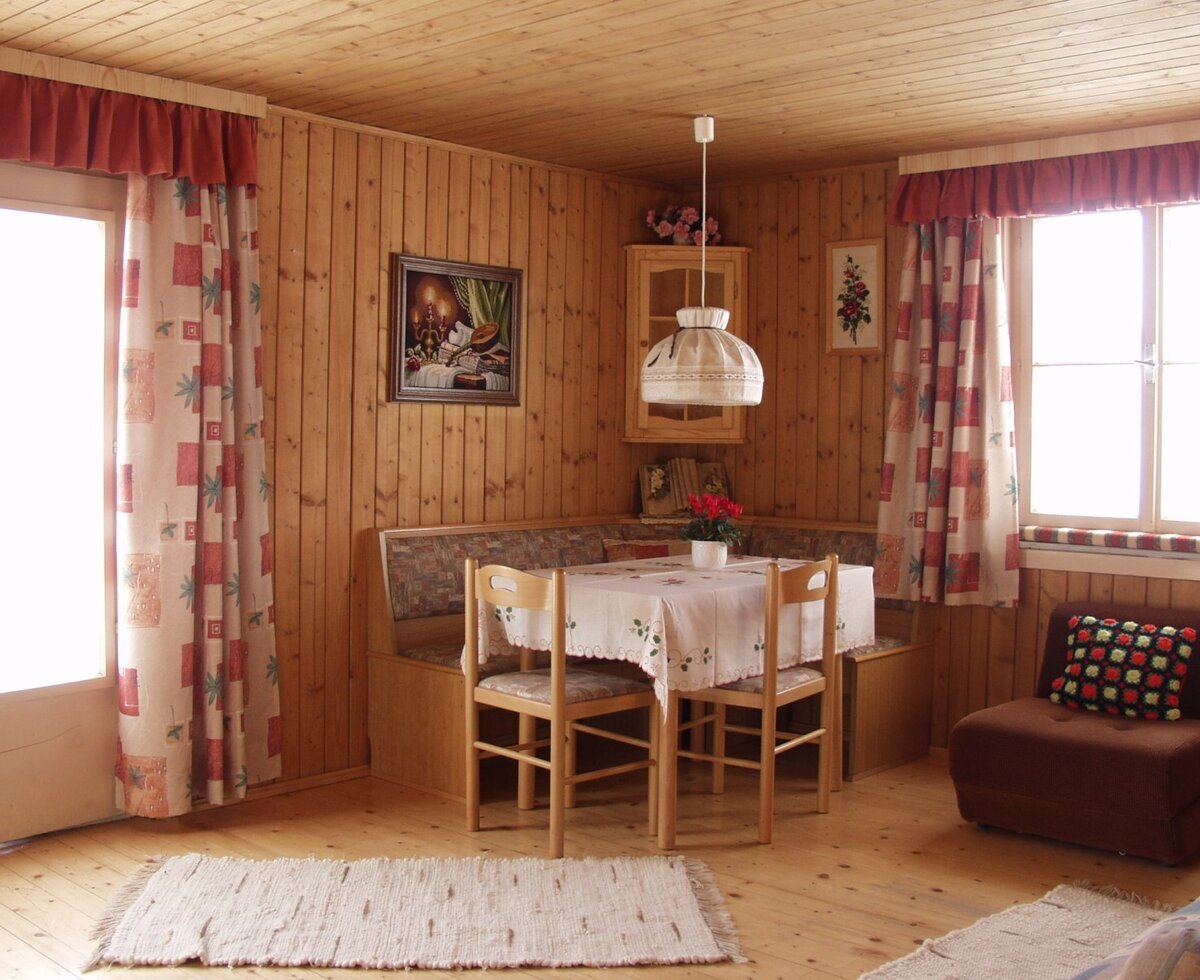The wood-panelled living room of the Farm House apartment, complete with a comfortable dining nook, a seating area, and balcony access.