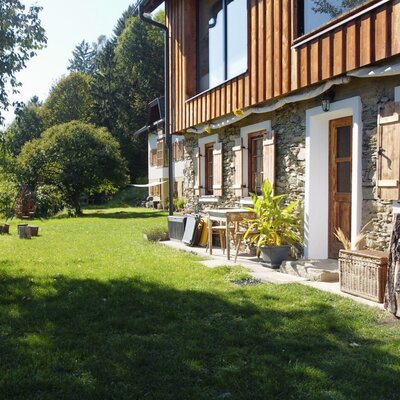 The garden of the farmhouse, featuring a large lawn, a picnic table, and a patio with seating.