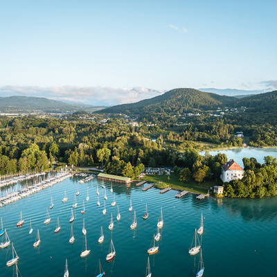 View of the lake with sailboats, an island featuring a building, and the surrounding mountains from the farmhouse.