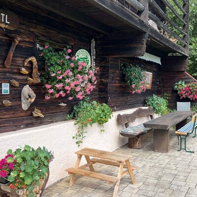 The farmhouse's inviting patio featuring rustic wooden benches and colorful flower displays.