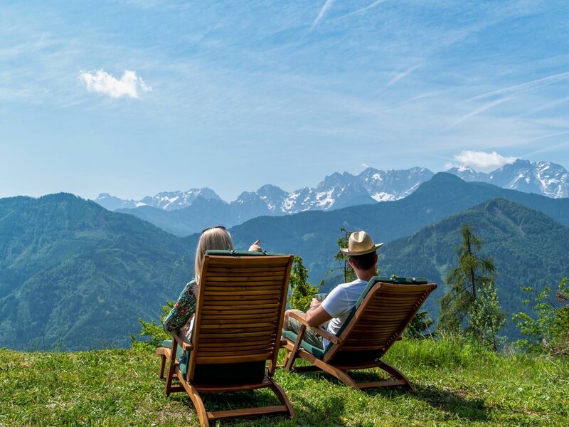 Guests enjoy panoramic mountain views from outdoor deck chairs at the Alpine Hut.