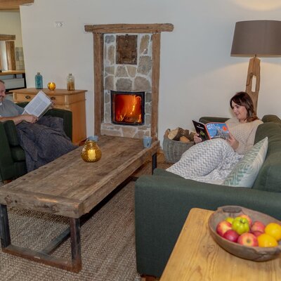 The Alpine Hut's living area features a stone fireplace, comfortable sofas, and a wooden coffee table.