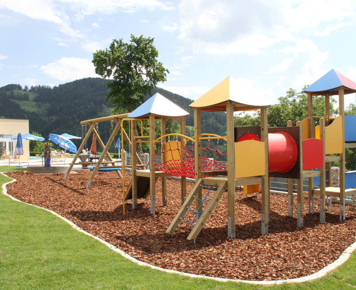 Playground with a swing, slide, climbing frame, and tunnel for the apartments.