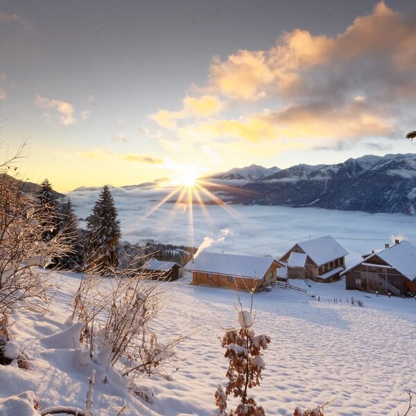 The Farm House buildings set against a snowy mountain backdrop, overlooking a misty valley during sunrise.