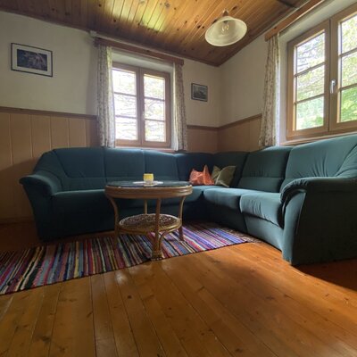 Living area in the Alpine Hut with a large sectional sofa, a rattan coffee table, and wooden floors and ceiling.
