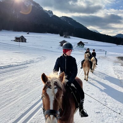 Horse riding through a snowy mountain landscape, an available activity at the farm house.