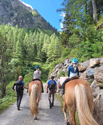 Horseback riding on a gravel path through a mountain forest, an activity available to guests of the Farm House.
