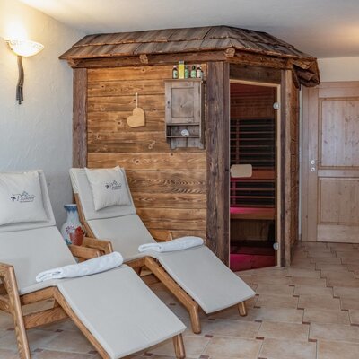 Sauna area of the farmhouse with a wooden cabin and two lounge chairs.