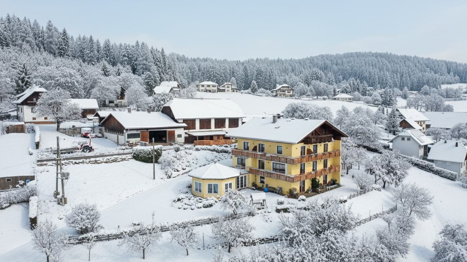 The Bauernhof in winter, surrounded by snow-covered fields and forests.