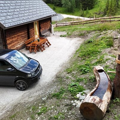 The rustic Alm features a convenient parking space right outside, along with a cozy outdoor seating area and a traditional wooden water trough.