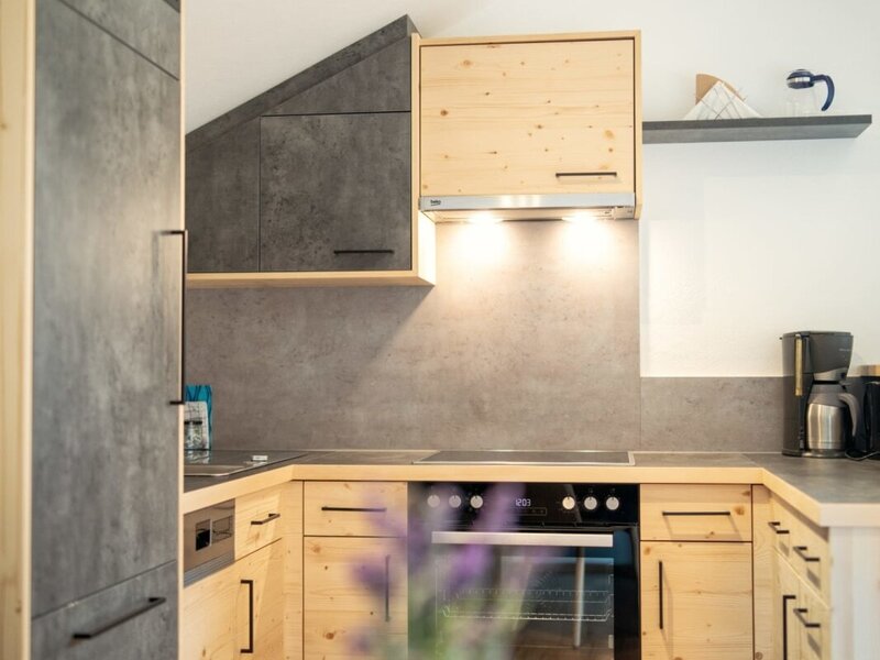 The U-shaped kitchen in the Farm House includes light wood cabinetry, dark countertops, a built-in oven, a dishwasher, and a refrigerator.