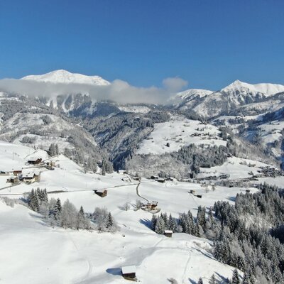 Winter landscape with snow-covered mountains, valleys, and scattered houses surrounding the farmhouse.