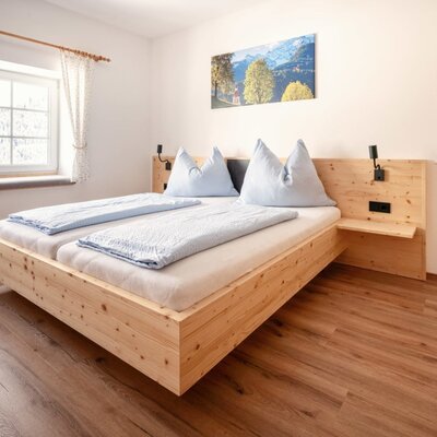 Additional double bedroom in the farmhouse with a wooden bed, integrated bedside tables, and a view of the snowy landscape.