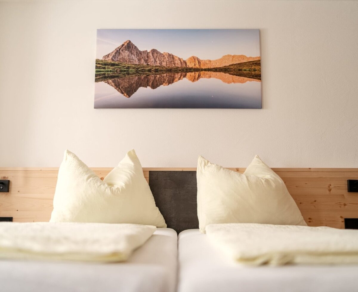 Farmhouse bedroom with a double bed, wooden headboard, reading lamps, and a landscape picture.