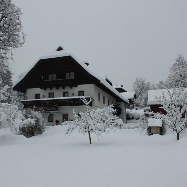 The exterior of the Farm House in winter, featuring balconies on the main building and snow-covered surroundings.