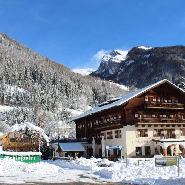 The main hotel building, featuring traditional architecture with balconies and a snow-covered mountain backdrop.