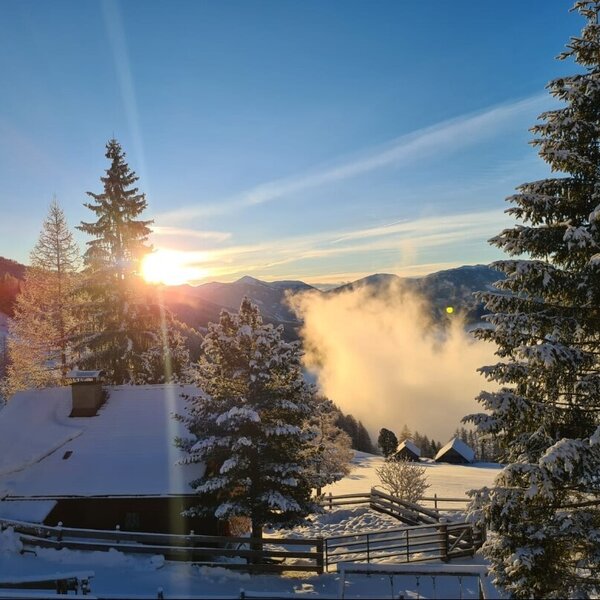 The Alpine Hut situated in a snow-covered winter mountain landscape with a low sun above valley clouds. The Alpine Hut situated in a snow-covered winter mountain landscape with a low sun above valley clouds.