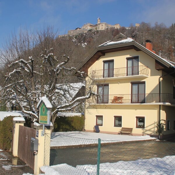 The Farm House SonnHOF, featuring balconies and a distant view of the hilltop castle, surrounded by winter snow. The Farm House SonnHOF, featuring balconies and a distant view of the hilltop castle, surrounded by winter snow.
