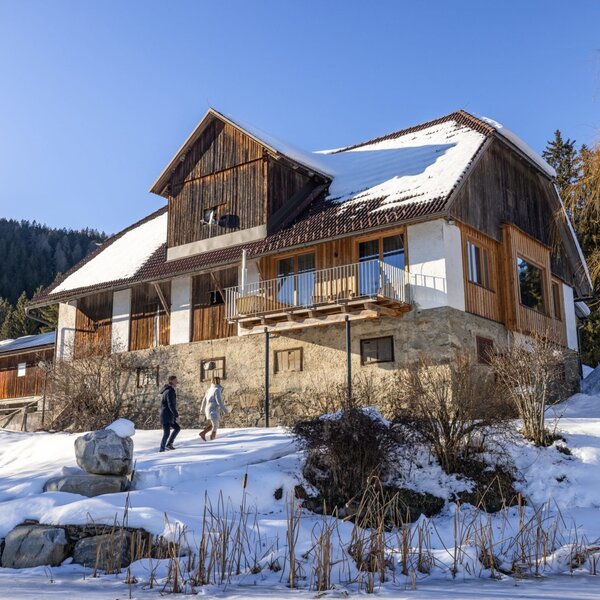 The exterior of the vacation rental, featuring a stone foundation and wooden upper levels with a balcony, set in a snowy landscape.