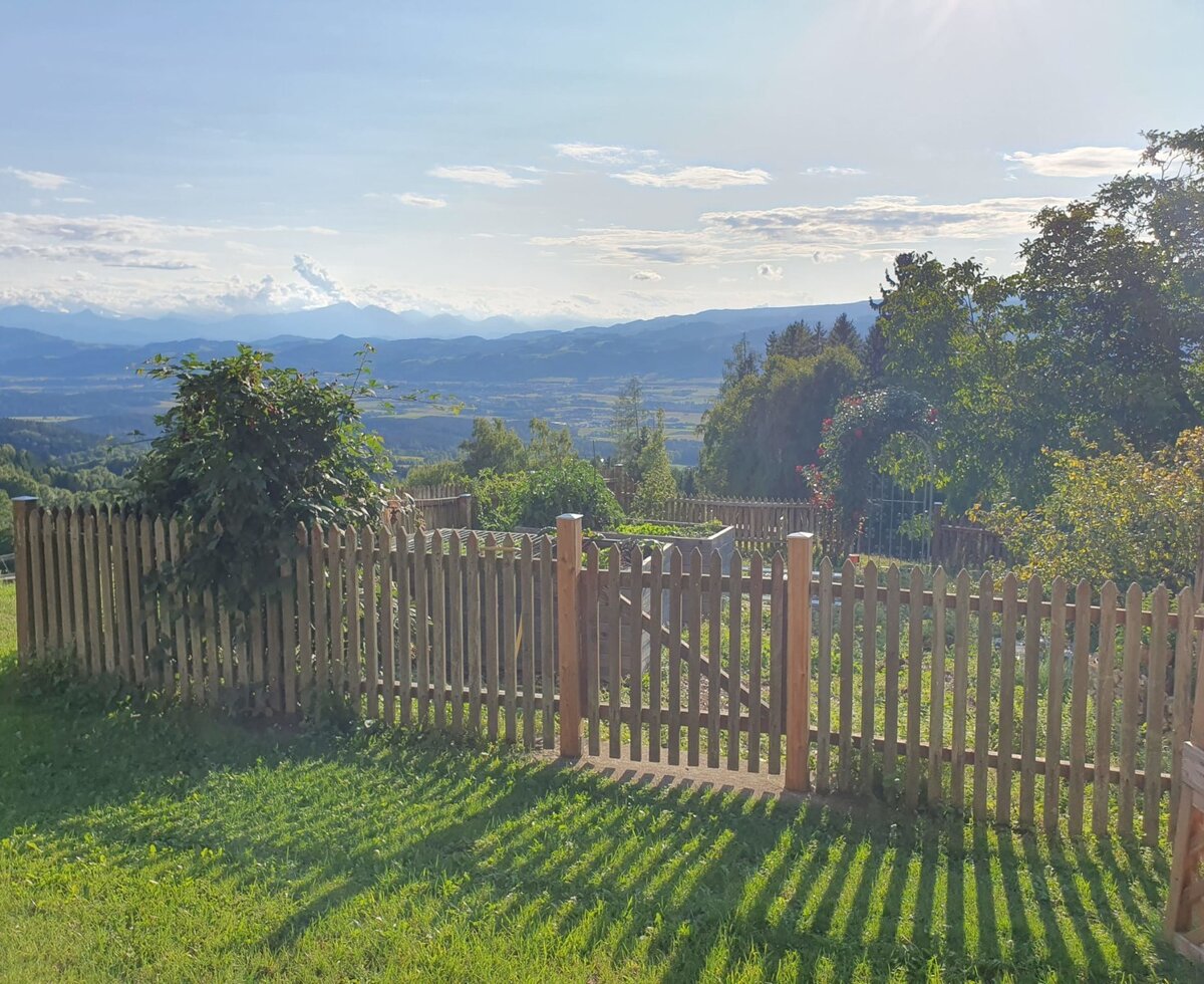 The farm house garden with a wooden picket fence and a view of the distant mountains and valley.