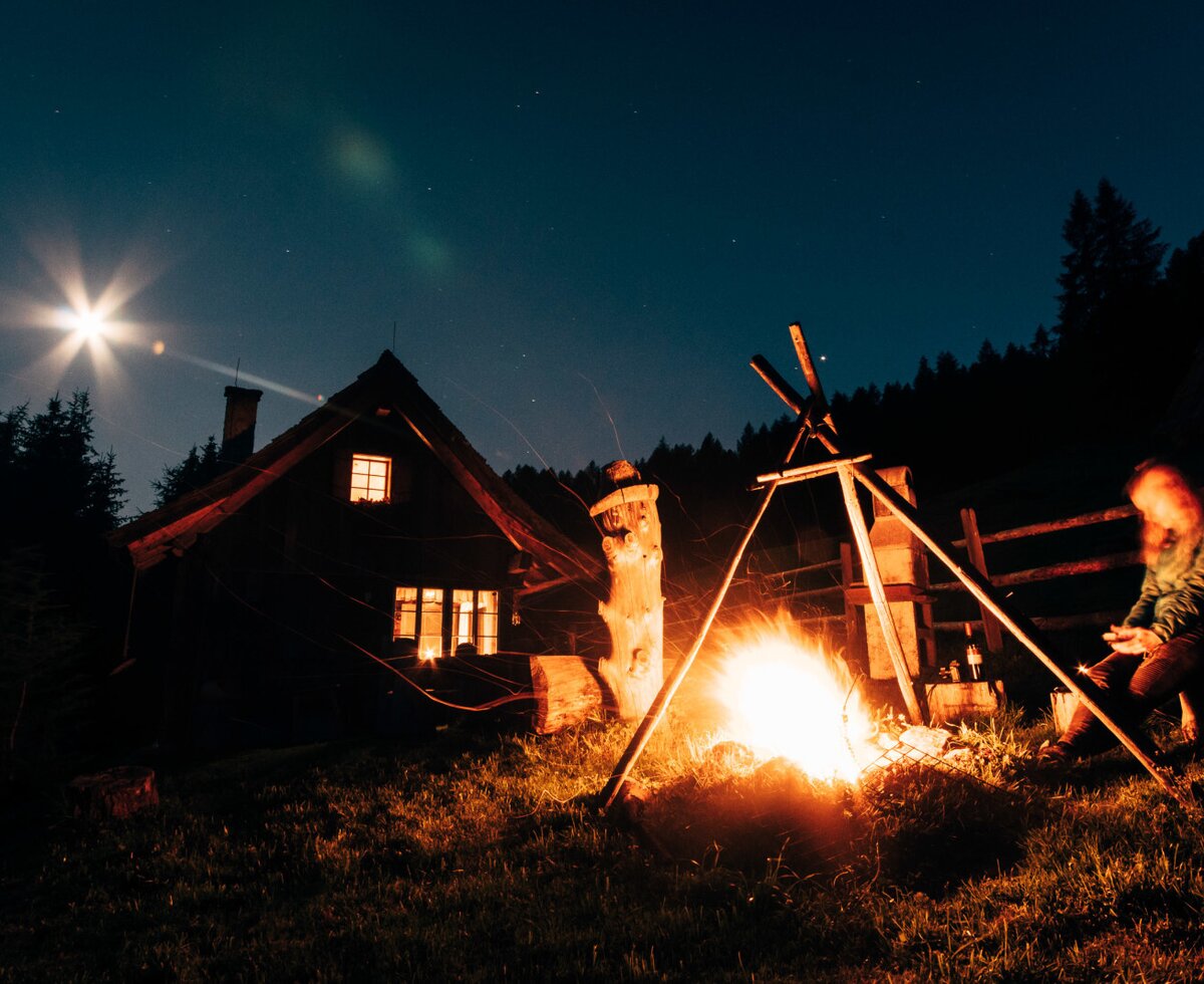 The Alpine Hut at night, featuring a bonfire area for guests to enjoy a campfire or barbecue.