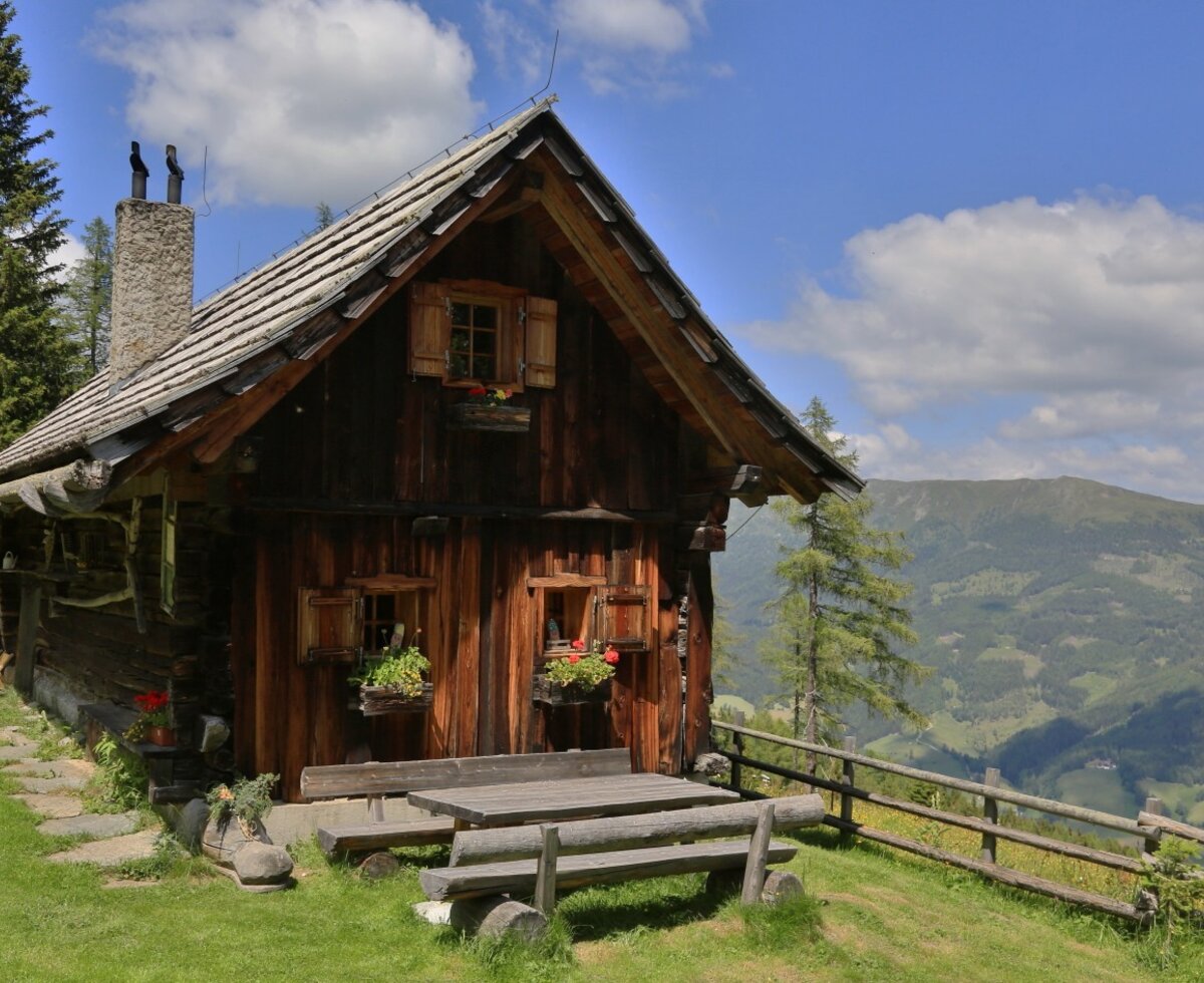 The cabin exterior, featuring an outdoor wooden table and benches for guests to enjoy the mountain views.