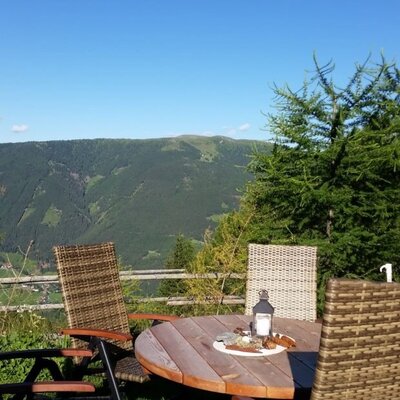 The cabin's inviting outdoor seating area, featuring a rustic wooden table and comfortable chairs with scenic mountain views.
