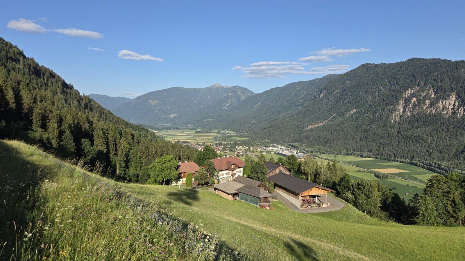 The farmhouse's idyllic location on a lush green hillside, offering sweeping views of the valley and the surrounding mountains.