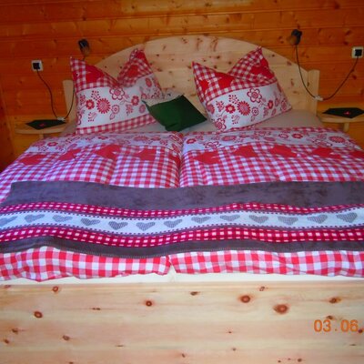 Double room in the Alm featuring a Swiss stone pine bed and traditional bedding.