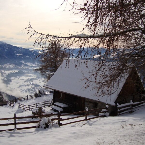 The snow-covered Alpine Hut, surrounded by a wooden fence, offers views of the snowy valley and distant mountains. The snow-covered Alpine Hut, surrounded by a wooden fence, offers views of the snowy valley and distant mountains.