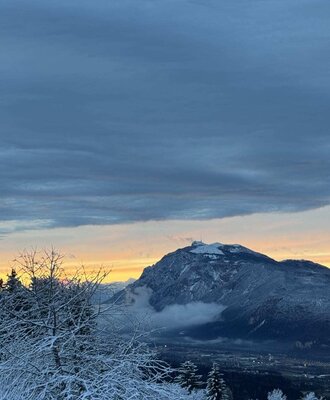 View from the farmhouse of snowy mountains and trees at sunset.