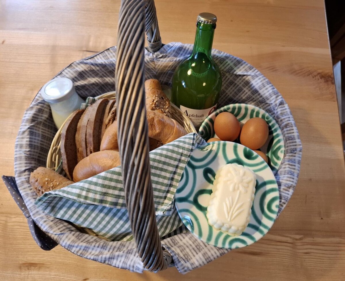A breakfast basket available at the Farm House, containing bread, rolls, butter, eggs, apple juice, and a jar of yogurt.