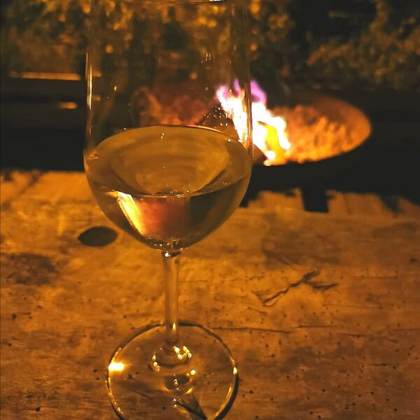 White wine on a wooden surface with a fire pit in the background at the farmhouse.