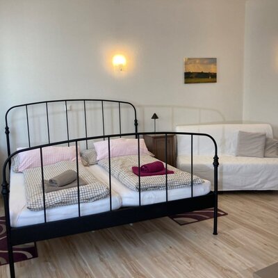 Double bedroom in the farmhouse with a black metal bed, two bedside tables, and a sofa bed.