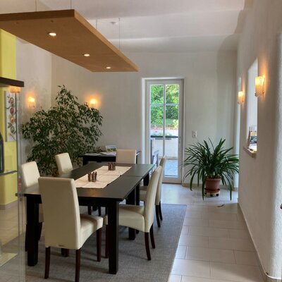 The dining area in the farmhouse features a long dark wood table with 8 cream chairs, and a glass-paned door leading outdoors.