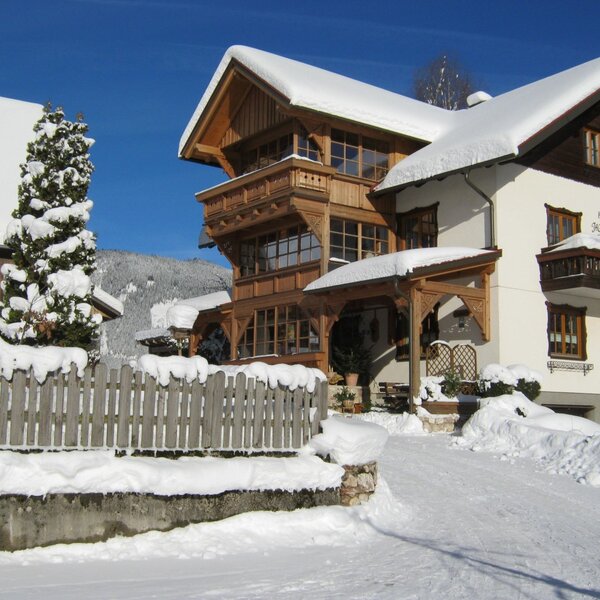 The Farm House exterior with snow-covered roofs, traditional wooden balconies, and a clear winter entrance.