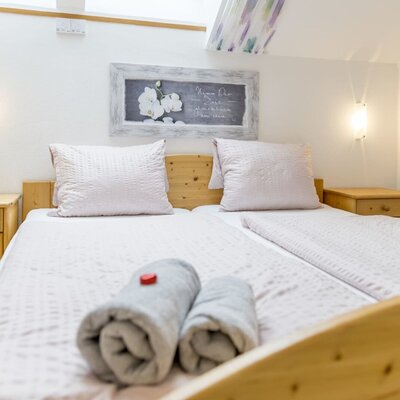 Bedroom in the house with two single beds, wooden bedside tables, and wall lights.