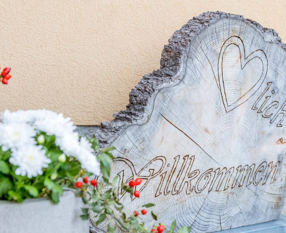 Wooden sign with 'Welcome' and a heart at the entrance of the Haus.
